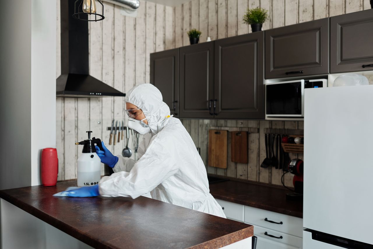 Un agent équipé d’un matériel de protection désinfecte une cuisine afin de garantir un environnement propre et sûr.